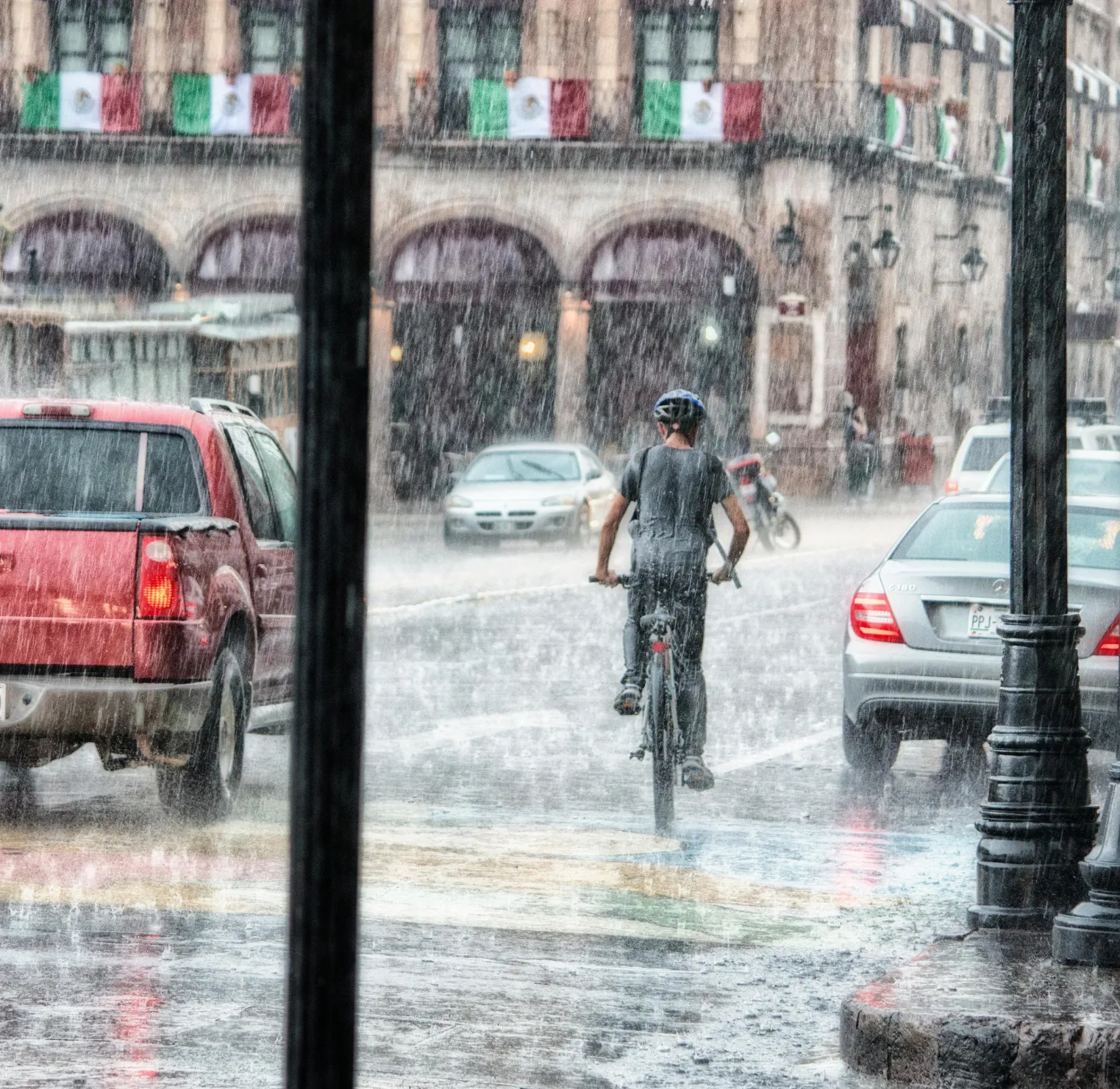 A man riding a bike down a rain soaked street.